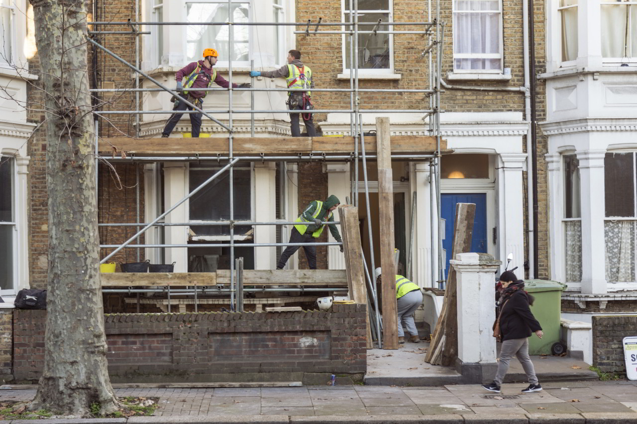 Four workers collaborate to build a scaffold during the refurbishment of a residential premises